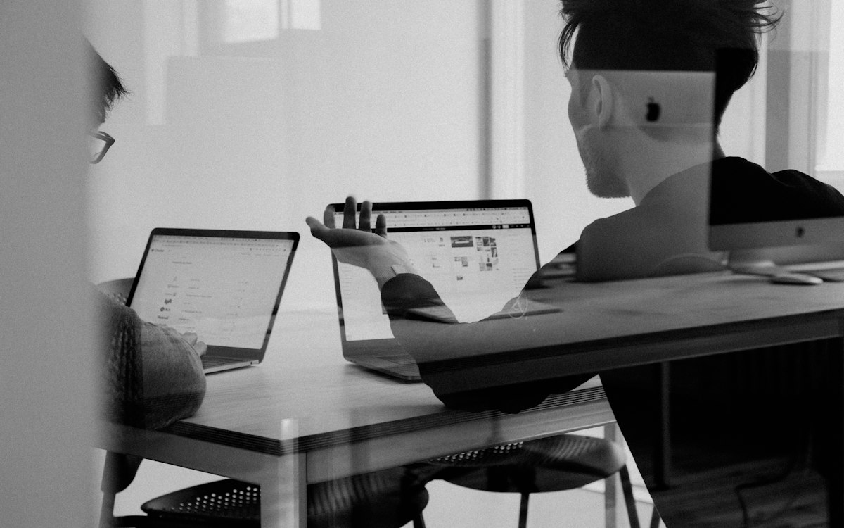 Two people reviewing work on their laptop screens.