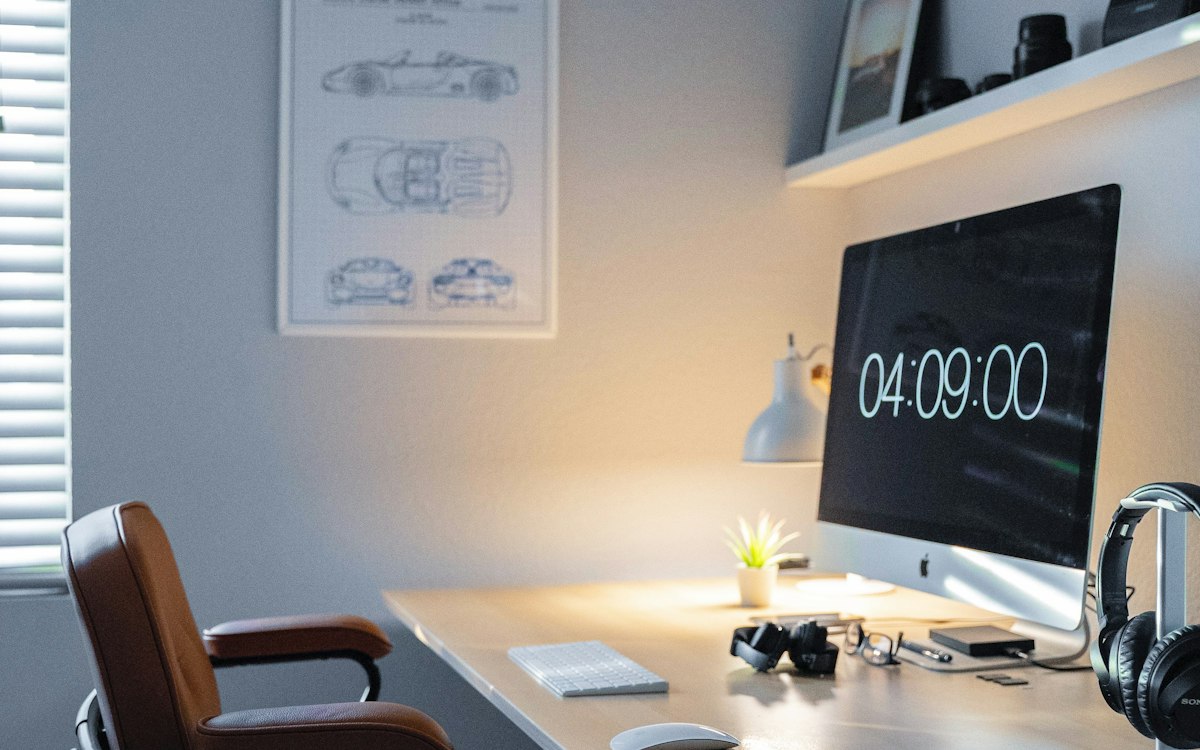 A home office with a digital clock and computer monitor.