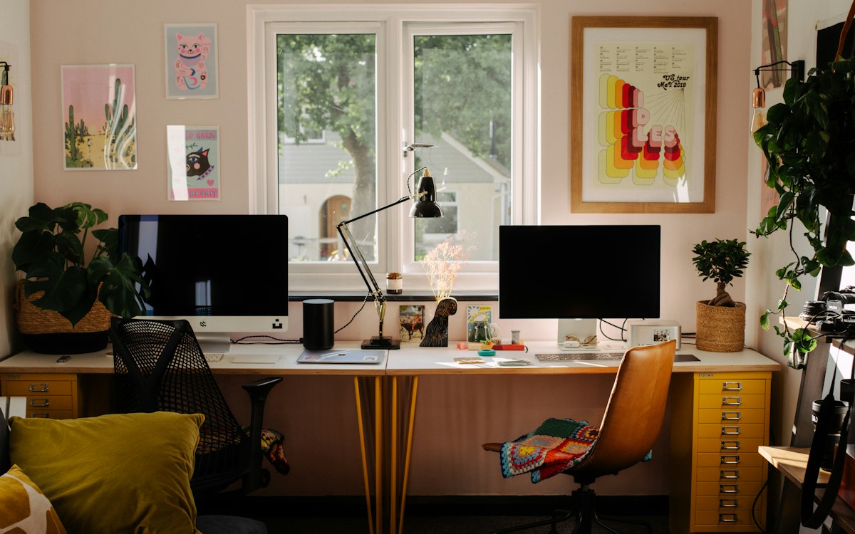 A creative home office with plants, artwork and natural light.