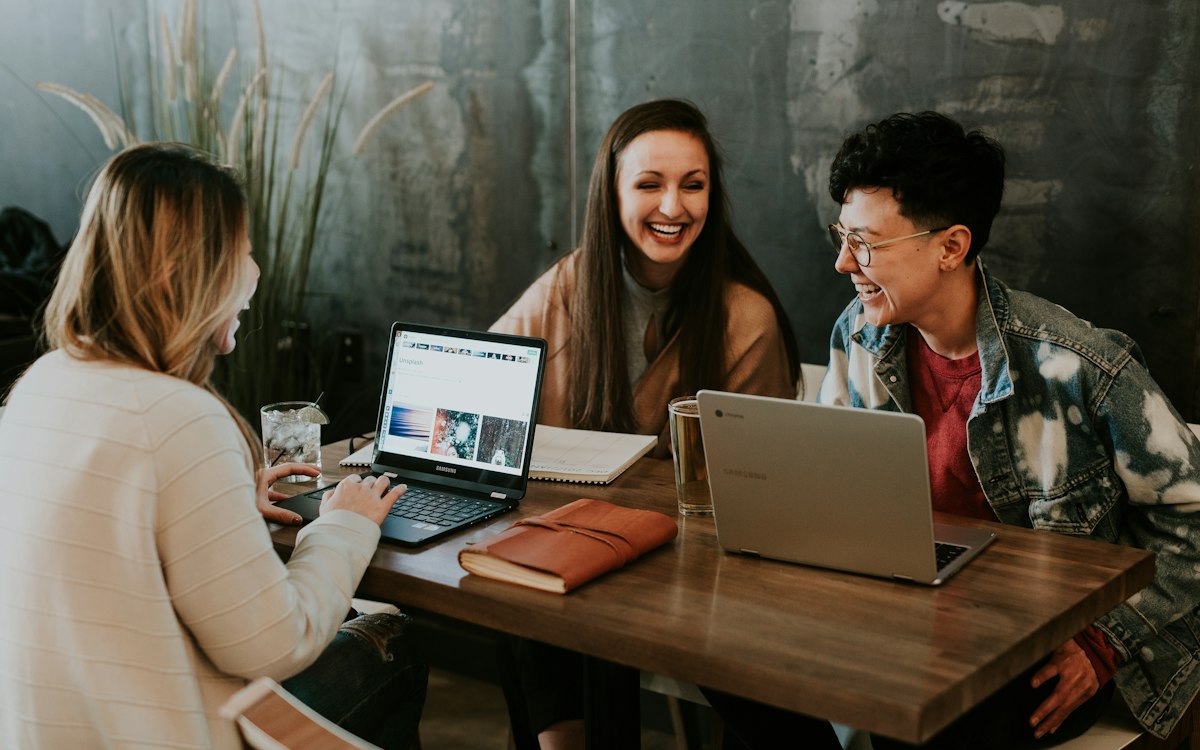 Three people collaborating around a laptop at a table.