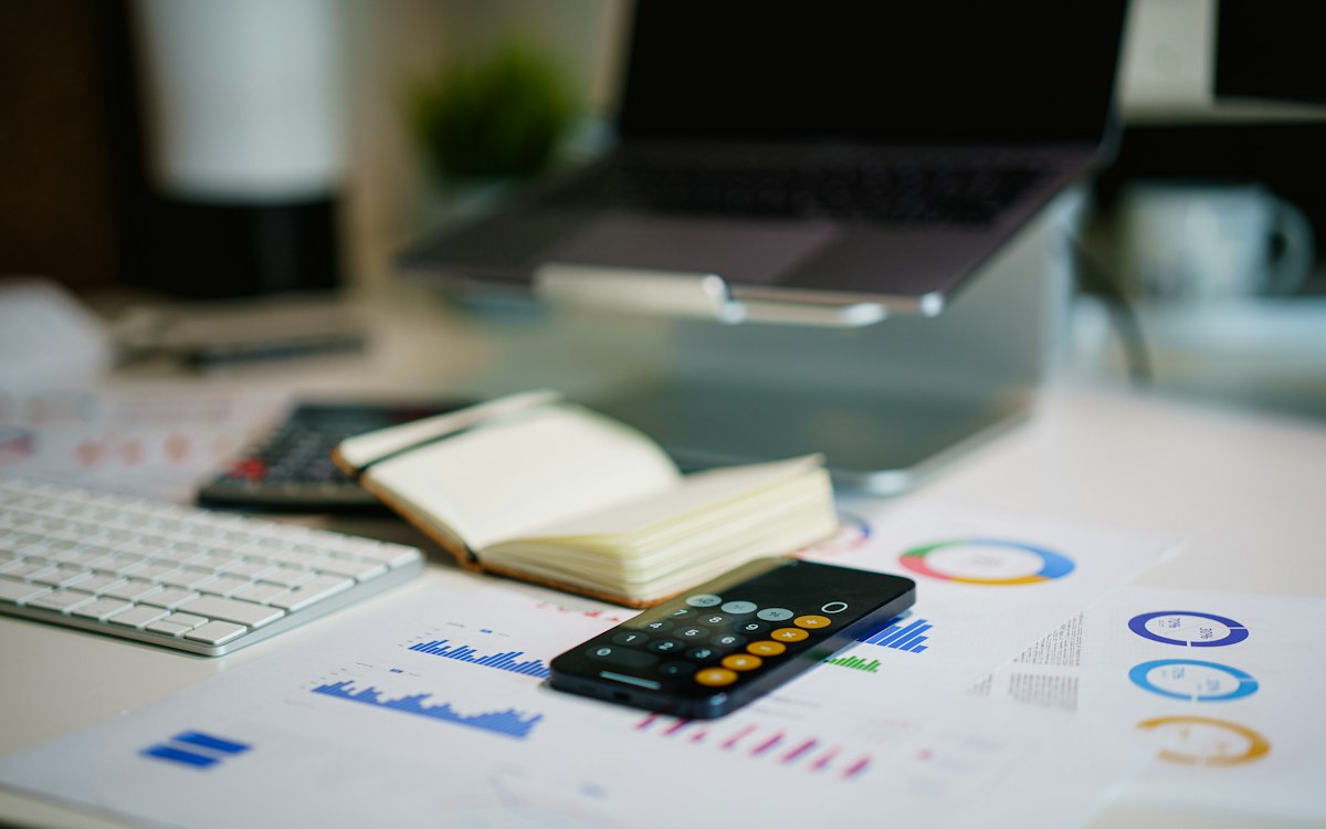 Printed charts, a calculator and a notebook on a desk.