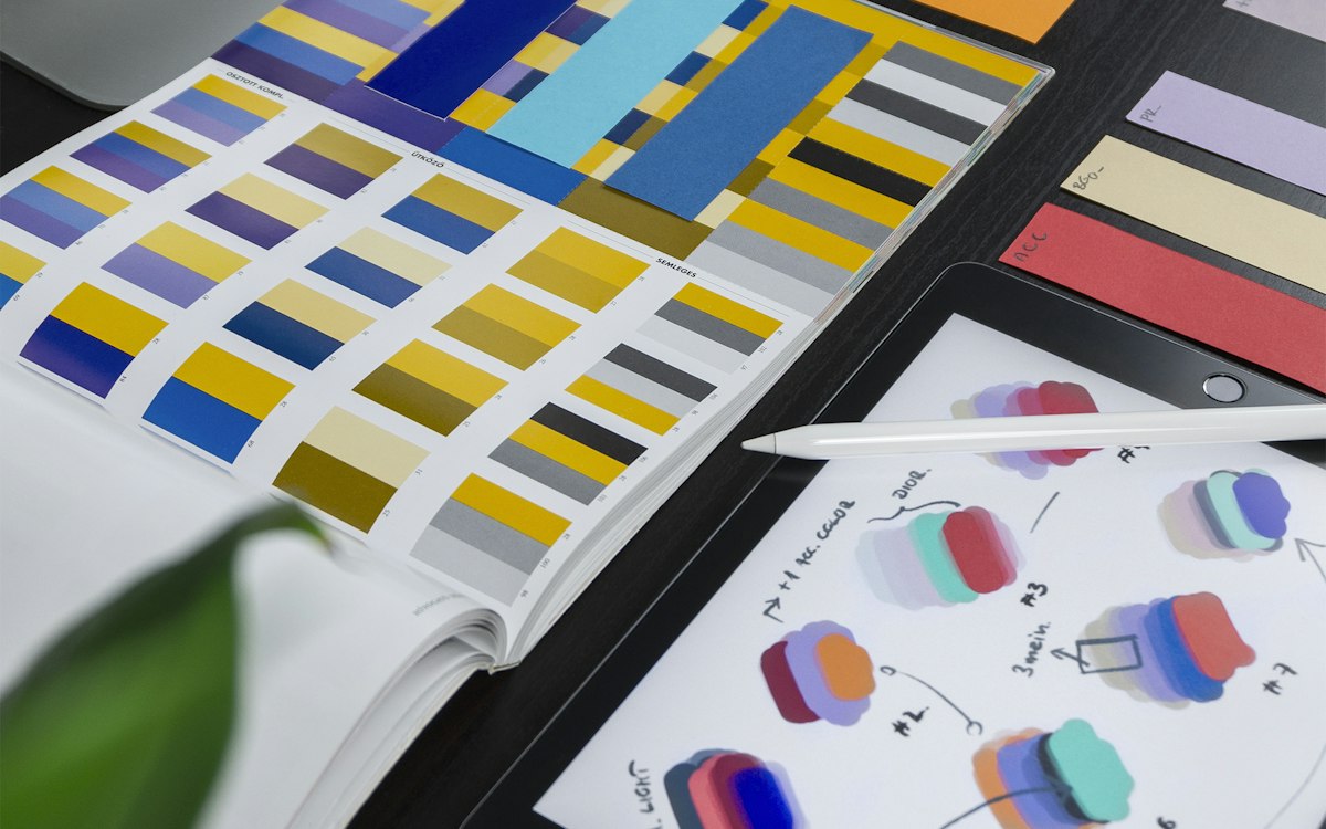 Color swatches and printed design layouts spread on a table.