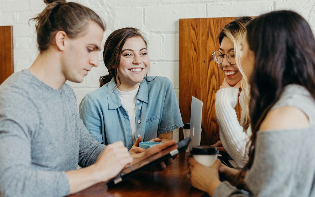 Three people sharing a conversation around a tablet.