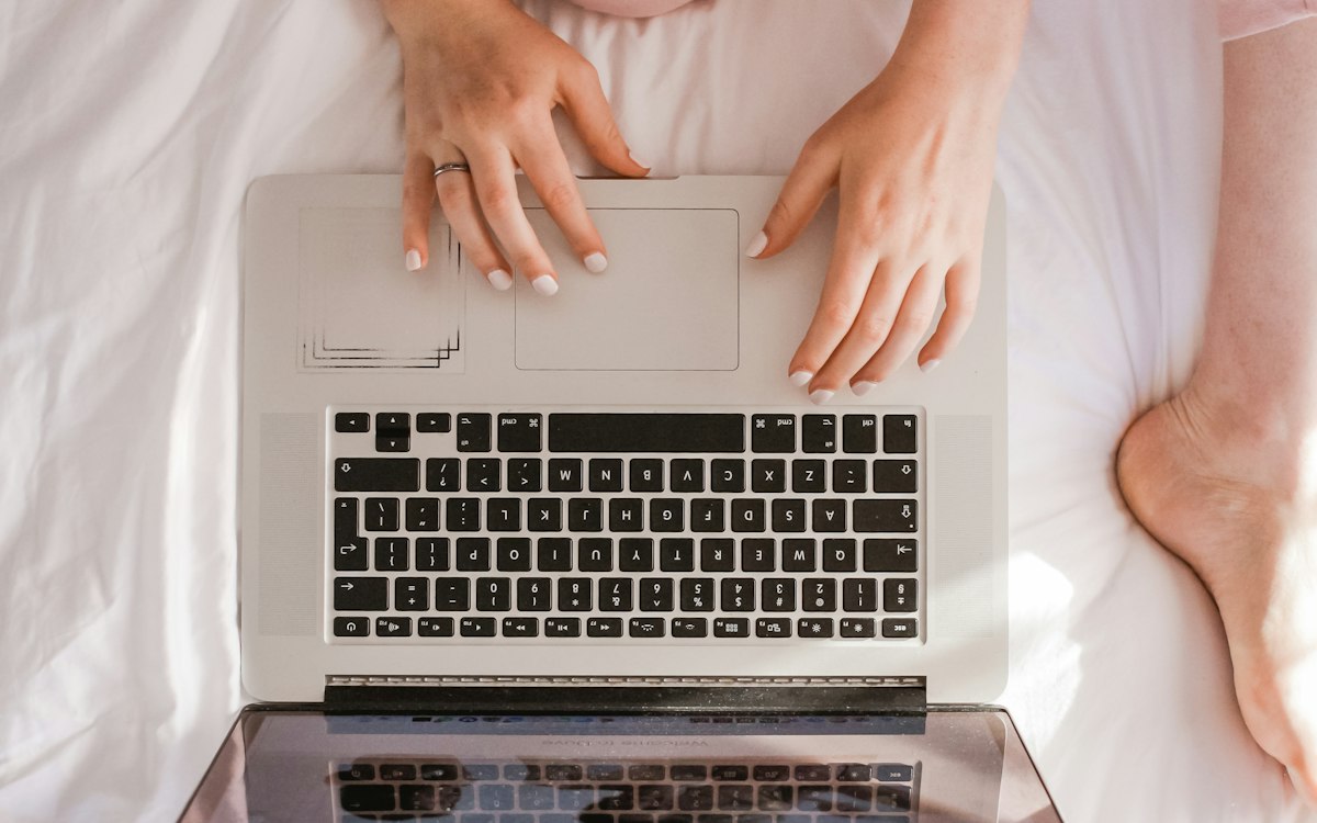 Hands typing on a laptop viewed from above.