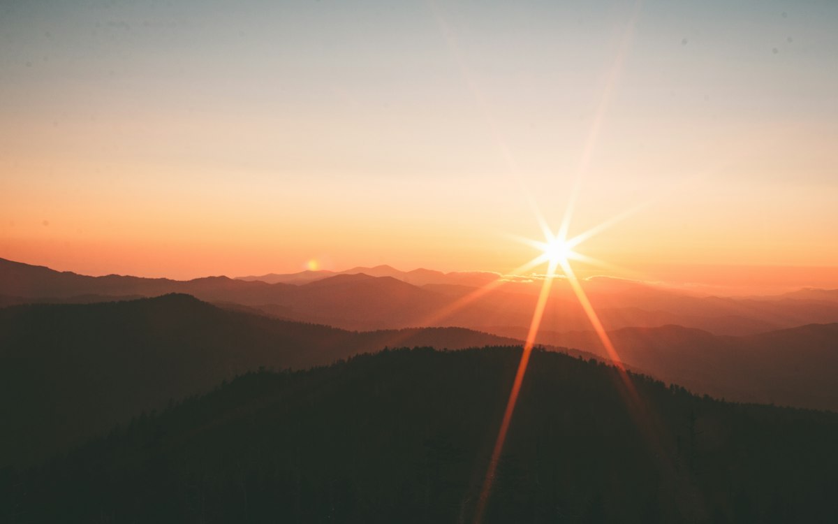 Sunrise breaking over a range of mountain ridges.