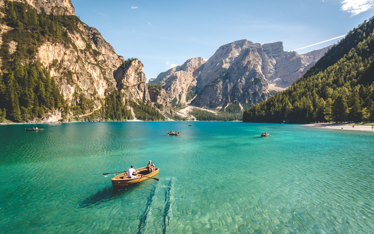A small rowboat on a turquoise lake surrounded by mountains.